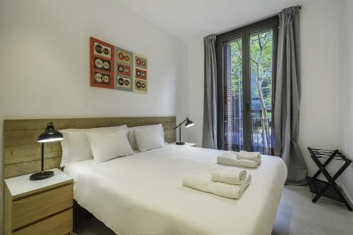 a bedroom with a large white bed with a window at The White Flats Sant Antoni in Barcelona