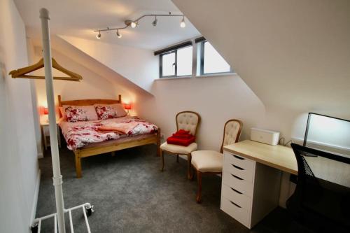 a bedroom with a bed and a desk in a attic at Spacious comfortable & private parking in town centre in Cheltenham