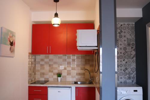 una cocina con armarios rojos y fregadero en Apartamentos La Carmen en Arrecife