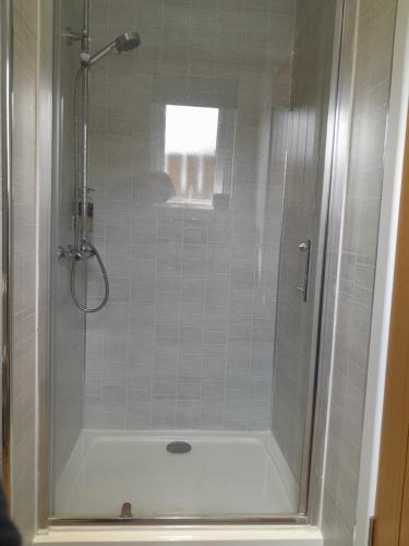 Glencoe view lodge في غلينكو: حمام مع دش مع حوض استحمام أبيض