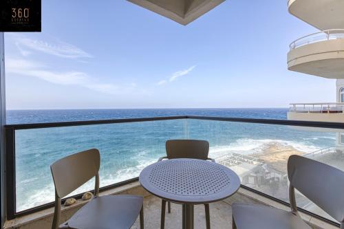 a table and chairs in a room with a view of the ocean at Tower Road Sliema, 4BR APT with sensational views by 360 Estates in Sliema
