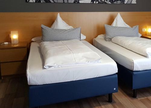 two beds in a hotel room with white and blue at Hotel & Restaurant Hüllen in Barweiler