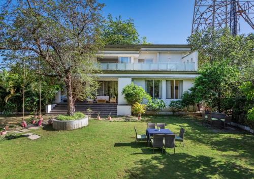 a house with a table and chairs in a yard at SaffronStays 7 Seas, Alibaug in Alibaug
