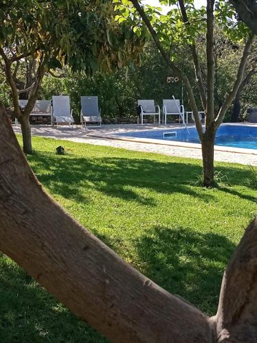 a fence in front of a pool with chairs and trees at Monte Papa Figos in Malhão