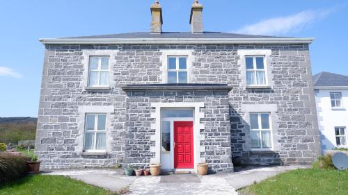 an old stone house with a red door at Kilmurvey House in Kilronan