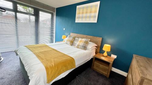 a bedroom with a large bed with blue walls at Cross Court, Stafford by BELL Apartments in Stafford