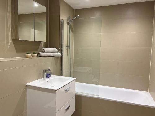 La salle de bains blanche est pourvue d'un lavabo et d'une douche. dans l'établissement Modern 1 bedroom flat high street, great location, à Hemel Hempstead