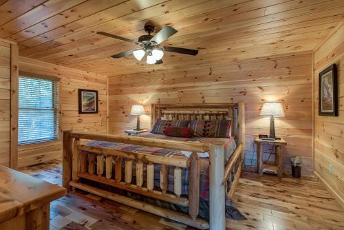 a log cabin bedroom with a bed and a ceiling fan at Rocky Top Lookout, 4 BR, Theater, Arcade, Bumper Pool, Hot Tub, Sleeps 12 in Gatlinburg