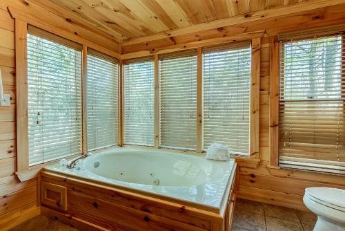 a bathroom with a tub and a toilet and windows at Rocky Top Lookout, 4 BR, Theater, Arcade, Bumper Pool, Hot Tub, Sleeps 12 in Gatlinburg
