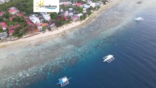two boats in the water next to a beach at Strandhaus Condotel in Moalboal