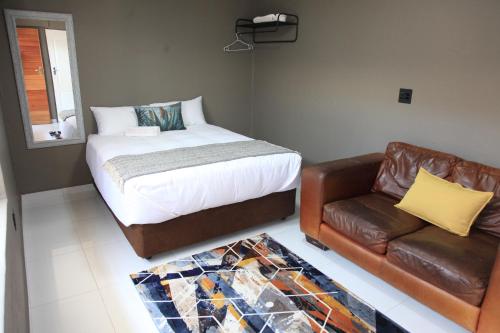 a bedroom with a bed and a leather couch at 4447 Guesthouse in Pimville
