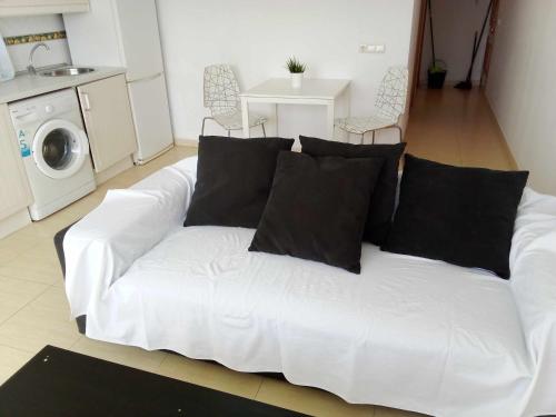 ein weißes Sofa mit schwarzen Kissen im Wohnzimmer in der Unterkunft Apartamento de 1 dormitorio en Calle Vela in Benalmádena