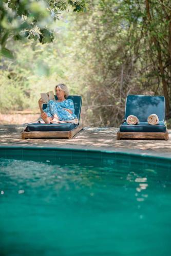 a woman sitting in a chair next to a swimming pool at Leopard Safaris Yala in Yala