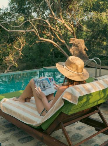 a woman in a hat reading a book on a beach chair at Leopard Safaris Yala in Yala