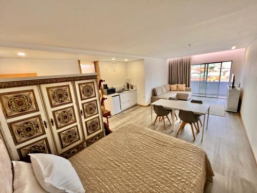 a bedroom with a bed and a table and a kitchen at Charming Studio Apartment in Povoa de Varzim in Póvoa de Varzim