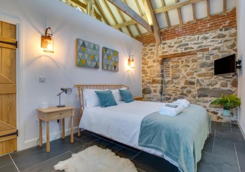 a bedroom with a bed and a stone wall at Bedwen in Llanfihangel-geneuʼr-glyn