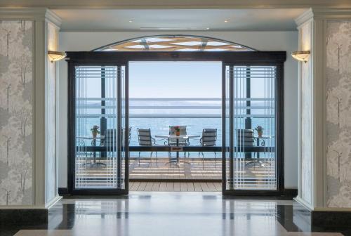 a room with a large glass door with a view of the ocean at Ramada by Wyndham , Athens Club Attica Riviera in Mati