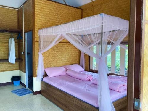 a bedroom with a canopy bed with pink pillows at Phonphusang Utopia Farmstay 