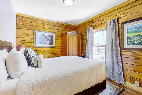a bedroom with a white bed and a window at Schroon River Adventures in Warrensburg