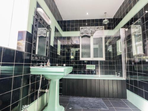 a black tiled bathroom with a sink and a tub at Crystal Cove in Bridlington