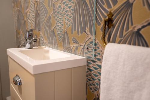 a bathroom with a sink and a towel at Stackyard Lodge - enchanting 18th Century converted barn in the Waveney Valley in Aldeby