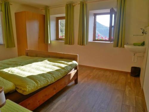 a bedroom with a bed and a sink and two windows at Enzianhuette Jaufenpass in San Leonardo