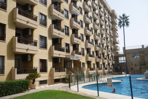 ein großes Apartmenthaus mit Pool davor in der Unterkunft Modern 1 Bed Seafront Apt Los Boliches in Fuengirola