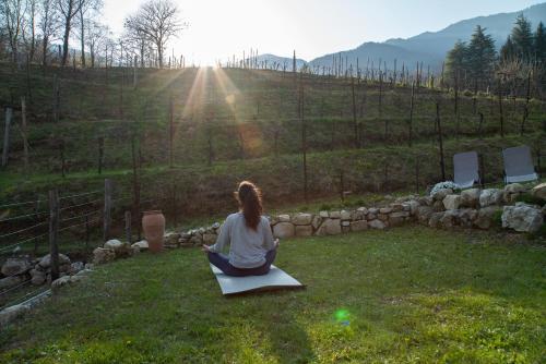 a woman sitting on the grass in a yoga pose at Agriturismo Podere del Bosc in Valmareno