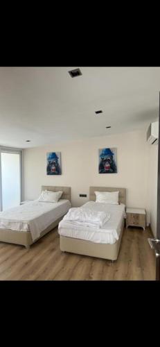 twee bedden in een kamer met witte muren en houten vloeren bij Elit semtte muhteşem konumda daire in Antalya