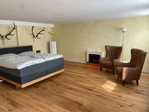 1 Schlafzimmer mit einem Bett und 2 Stühlen in der Unterkunft Jagdzimmer in Thalheim