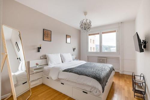 a white bedroom with a large bed and a mirror at Le Grand Fauriel 100m 6 places in Saint-Étienne