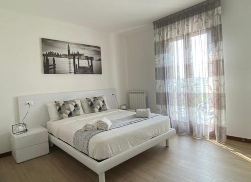 a white bedroom with a large bed and a window at Residence Outlet Vivaldi in Noventa di Piave