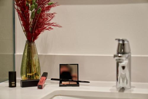 a bathroom sink with a vase with flowers in it at Sporthotel Grafenwald 4 Sterne Superior in Daun
