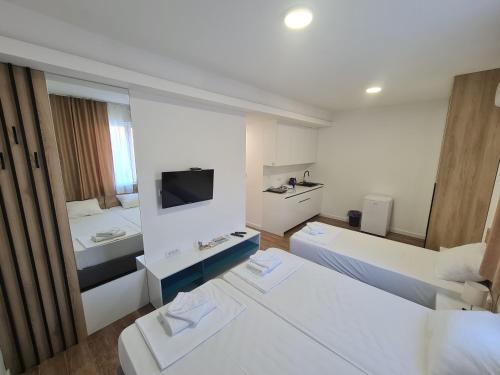 um quarto branco com 2 camas e uma televisão em Apartman Casa em Trebinje