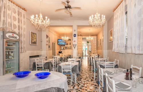 un restaurant avec des tables, des chaises et des lustres blancs dans l'établissement Hotel Stella Del Mare, à Viareggio