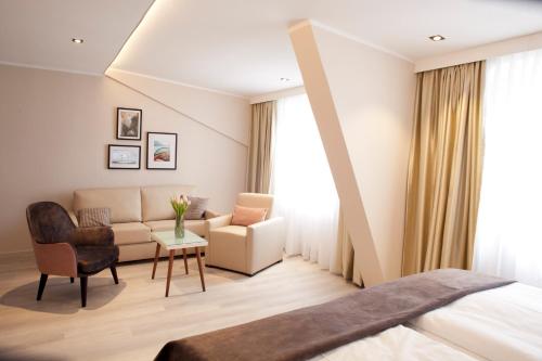 ein Hotelzimmer mit einem Bett und einem Sofa in der Unterkunft Hotel Schweriner Hof in Stralsund
