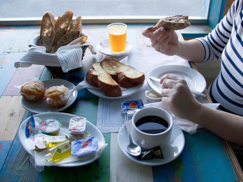 a table with a breakfast of toast and coffee and bread at Hotel Langosteira in Finisterre