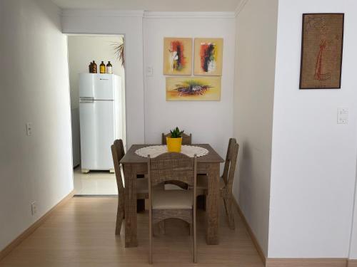 a dining room table with chairs and a white refrigerator at Apartamento Acolhedor e Bem Localizado in Vila Velha
