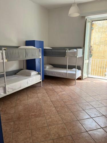 a room with three bunk beds and a tile floor at Coremi in Naples