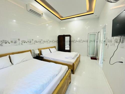 1 dormitorio con 2 camas y TV en la pared en Bảo Phúc Bungalow- Đảo Phú Quý, en Cu Lao Thu