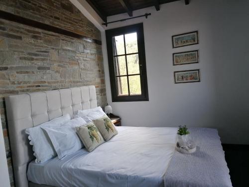 a bedroom with a white bed with a brick wall at Maronia Luxury Villa in Maronia