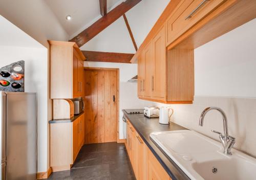 a kitchen with wooden cabinets and a sink at Beudyr Gelli in Trawsfynydd