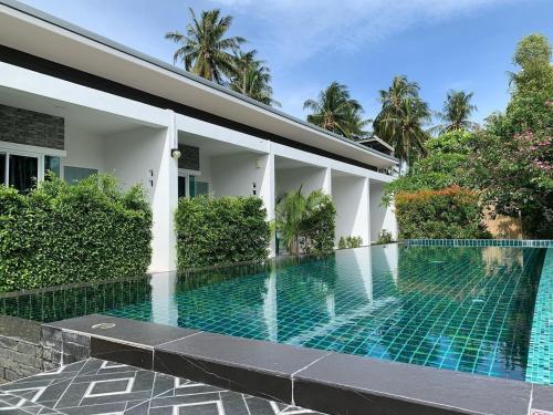 a swimming pool in front of a house at Phangan Hometown Resort - Adults Only in Baan Tai
