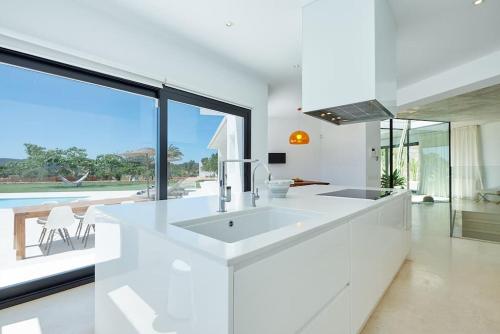 a white kitchen with a sink and a large window at Villa Can Pep de Sa Guaita in Sant Joan de Labritja