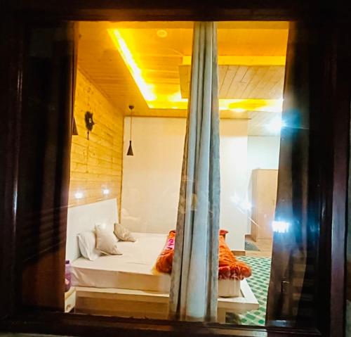 a view of a bedroom through a window at WildWoodHome Jibhi in Jibhi