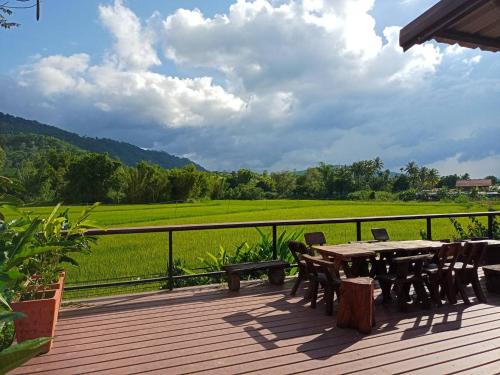 a wooden deck with a table and chairs and a field at ภูเรือวิว รีสอร์ท in Loei