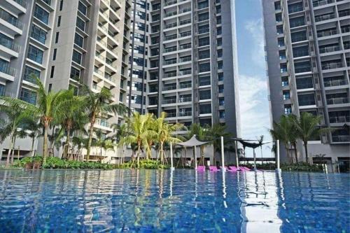 a swimming pool with palm trees and tall buildings at Atlantis Sea View Unit in Malacca