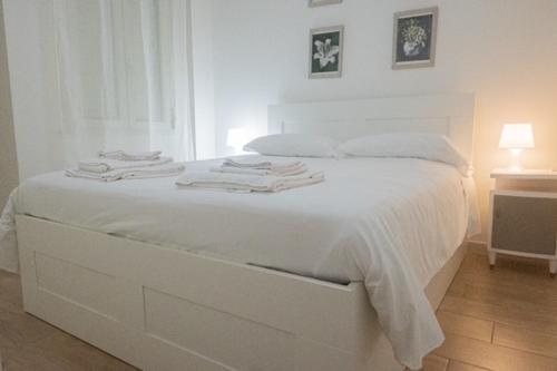 - un lit blanc avec des draps blancs et des serviettes dans l'établissement Villanova Apartment, à Cagliari