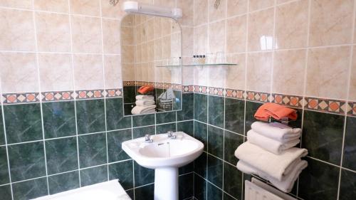 a green tiled bathroom with a sink and a mirror at Kilmurvey House in Kilronan