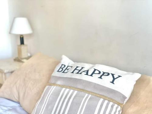 a pillow with the words be happy sitting on a bed at Departamento RIOJA in Paraná